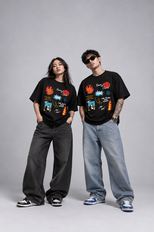 A man and a woman modeling matching black graphic t-shirts with colorful retro-style illustrations, paired with wide-leg jeans and sneakers, against a solid gray studio background.