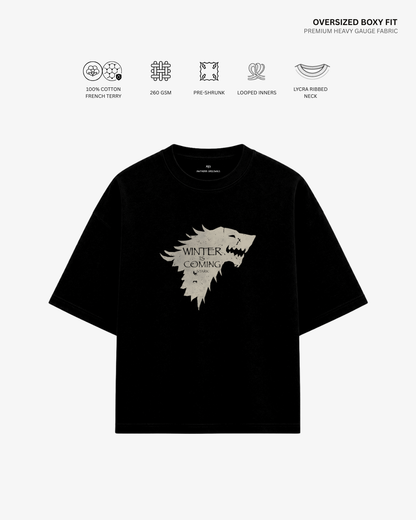 A black oversized short-sleeve T-shirt with a large light beige 'Winter is Coming' direwolf graphic on the front, shown on a light gray background with feature icons and text above.