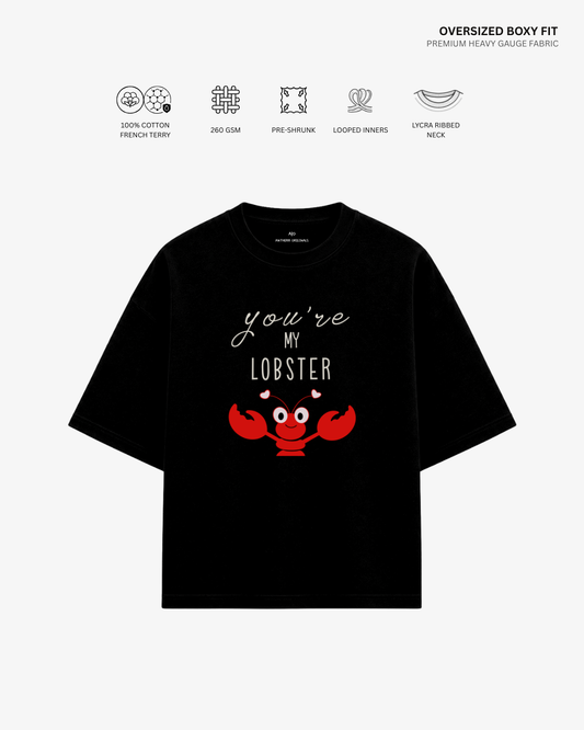 A black oversized short-sleeve T-shirt with a red lobster graphic and the text 'you're MY LOBBER' on the front, shown on a light gray background with feature icons and text above.